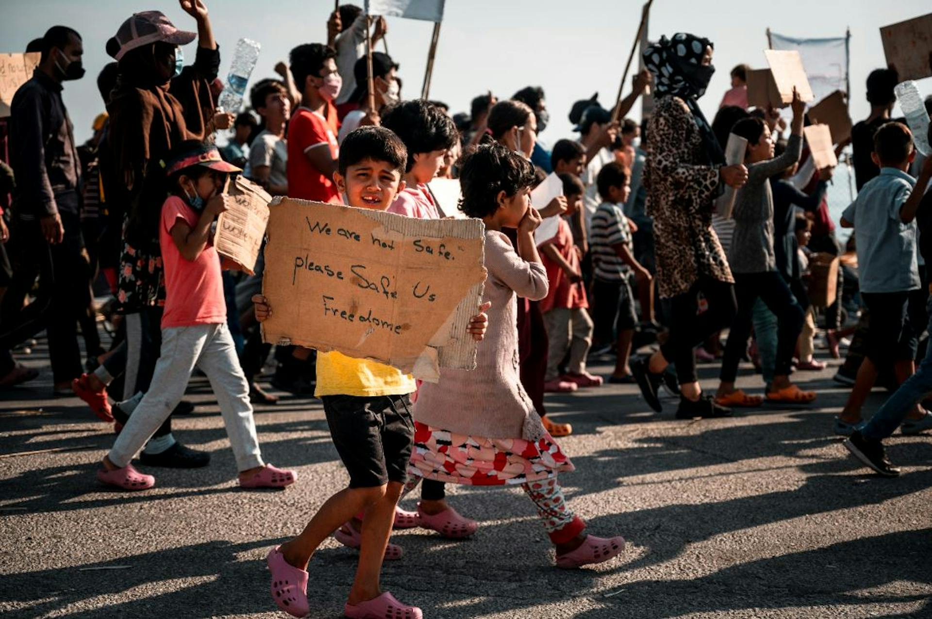 Protest waar jongen een kartonnen bord vasthoud met boodschap